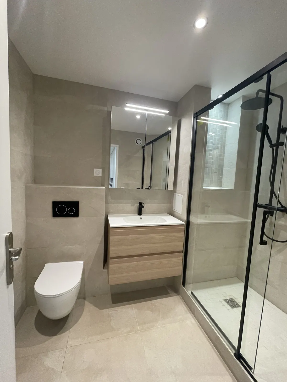 Salle d’eau beige avec WC suspendu et douche